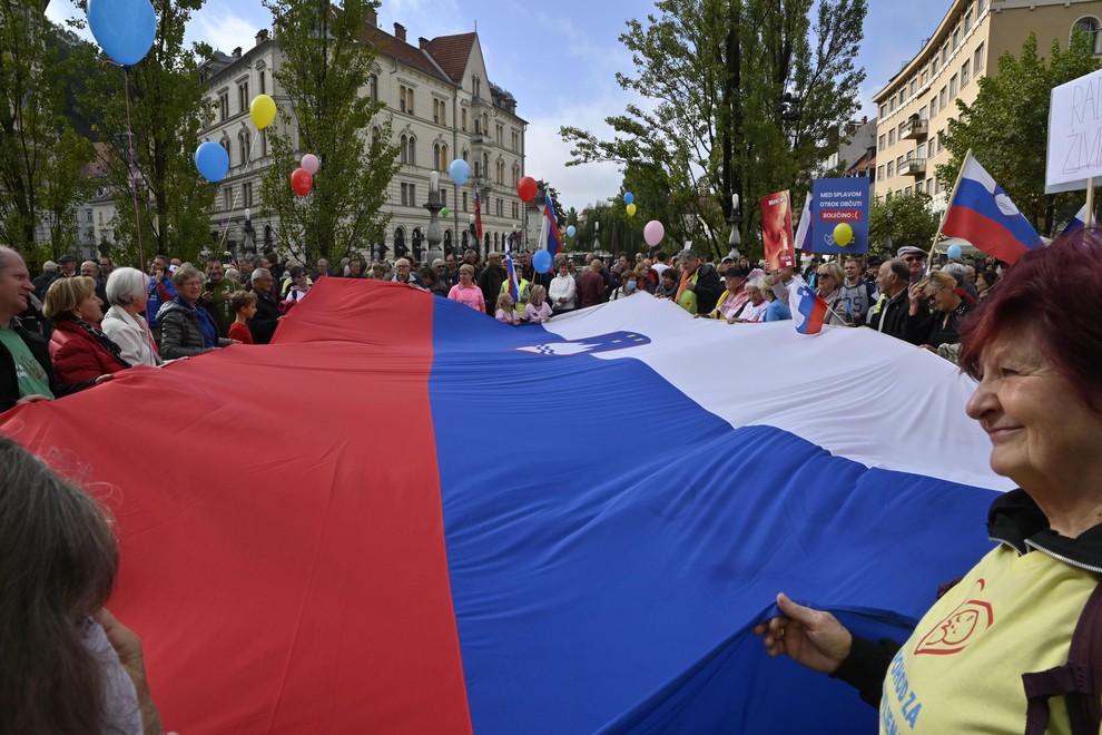 V središču Ljubljani se je zbrala množica ljudi z baloni in veliko slovensko zastavo.