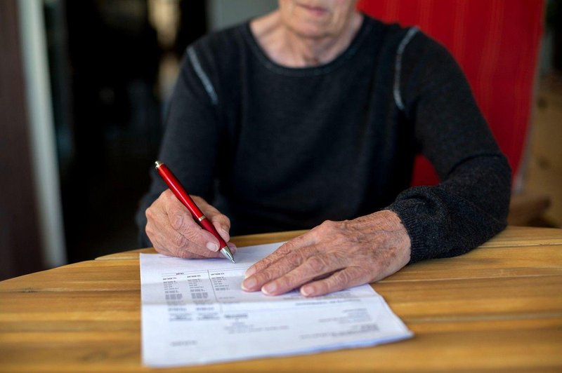 Starejša ženska podpisuje dokument (foto: Profimedia)